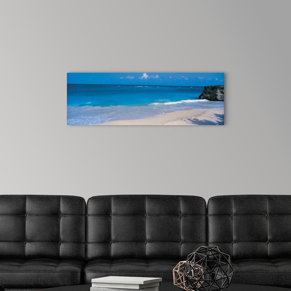 A modern room featuring This is a panoramic photograph of small waves breaking on a sandy tropical beach.