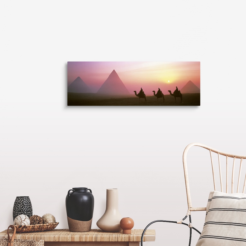 A farmhouse room featuring Panoramic photograph of three camel riders at dusk with pyramids in the background.  The sun is s...