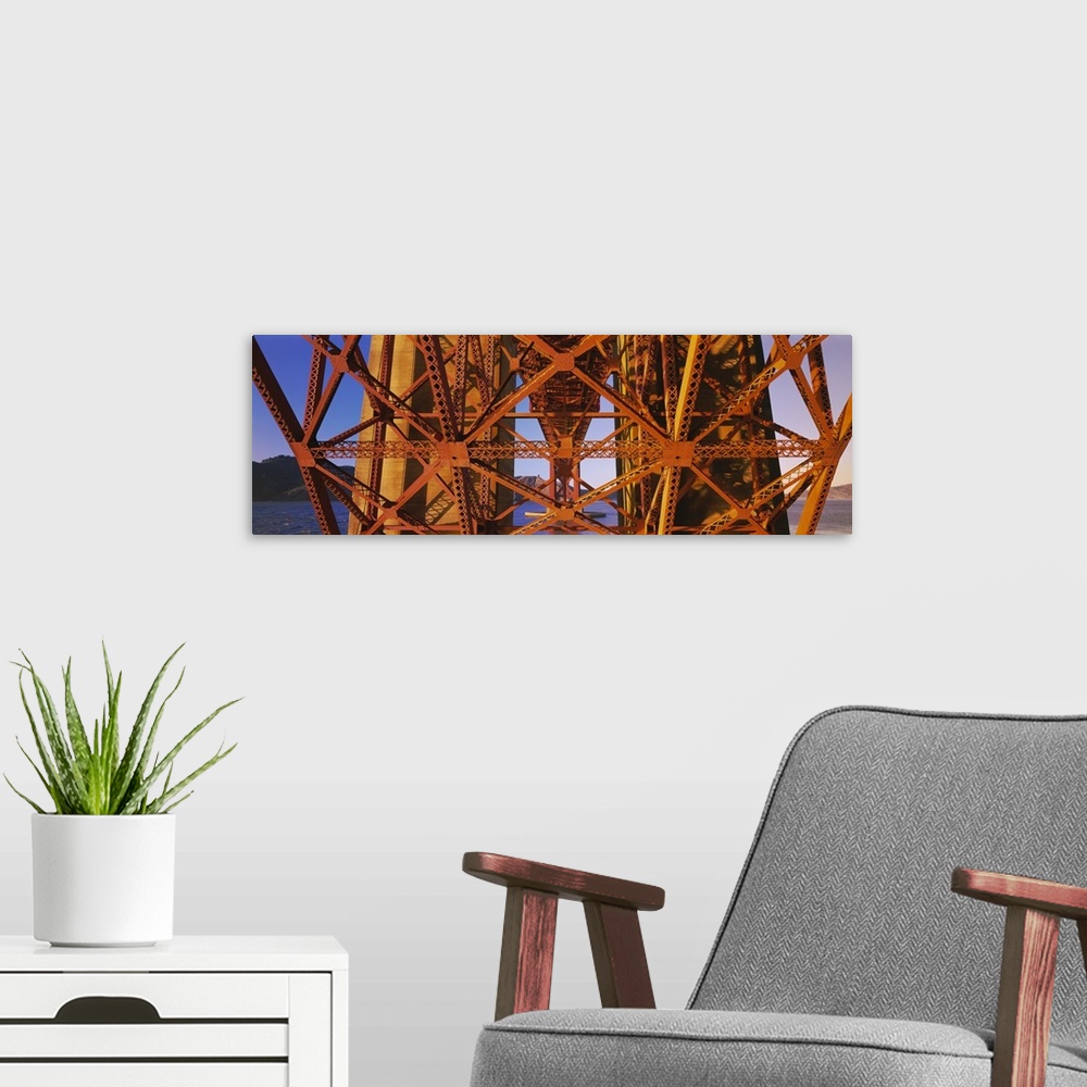 A modern room featuring Part of the Golden Gate bridge structure from below is photographed in wide angle view.