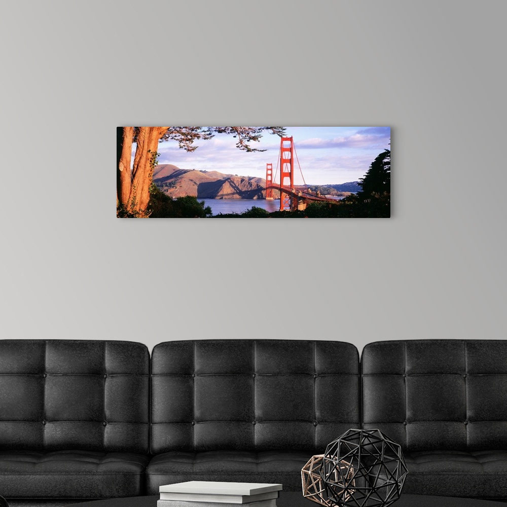 A modern room featuring This panoramic photograph shows a view of the suspension bridge and harbor through a park filled ...