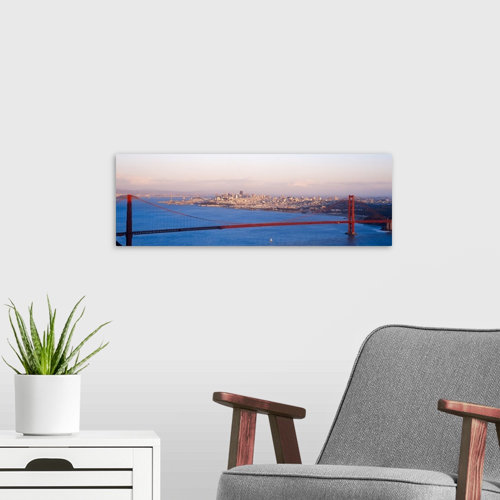 A modern room featuring An aerial photograph taken of the Golden Gate Bridge during sun down as half of the bridge is sha...
