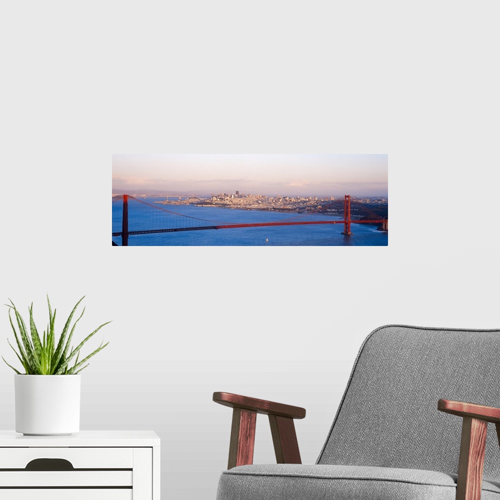A modern room featuring An aerial photograph taken of the Golden Gate Bridge during sun down as half of the bridge is sha...