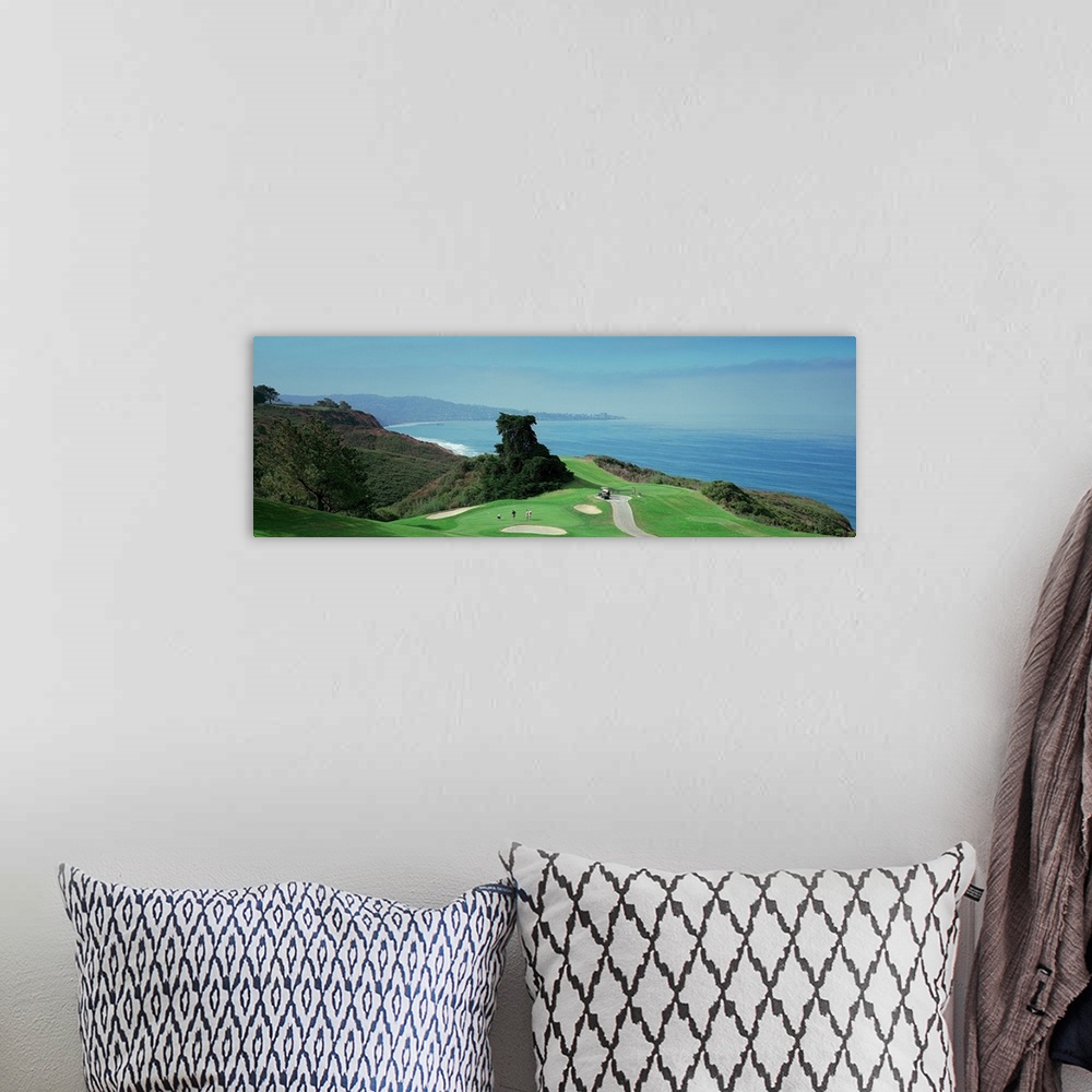 A bohemian room featuring This wall hanging is a panoramic photograph of a golf green overlooking the ocean from the top of...