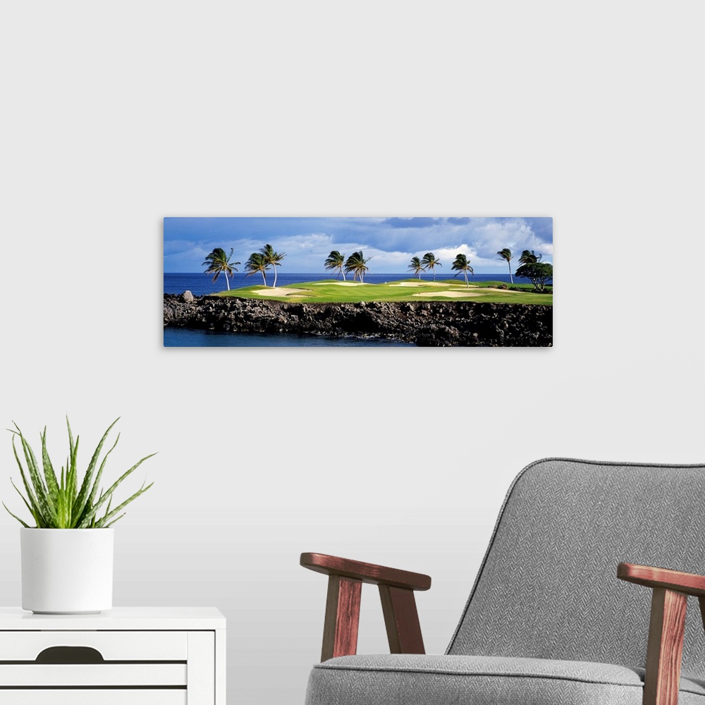 A modern room featuring Panoramic photograph of golf course on a rock cliff stretching into the ocean on a cloudy day.  T...