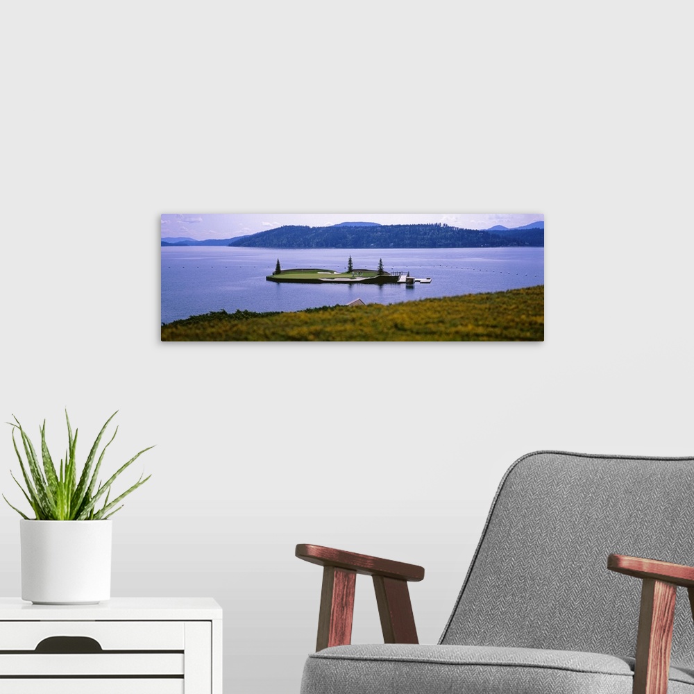 A modern room featuring Panoramic photo on canvas of a golf course on a small island in the middle of a lake with mountai...