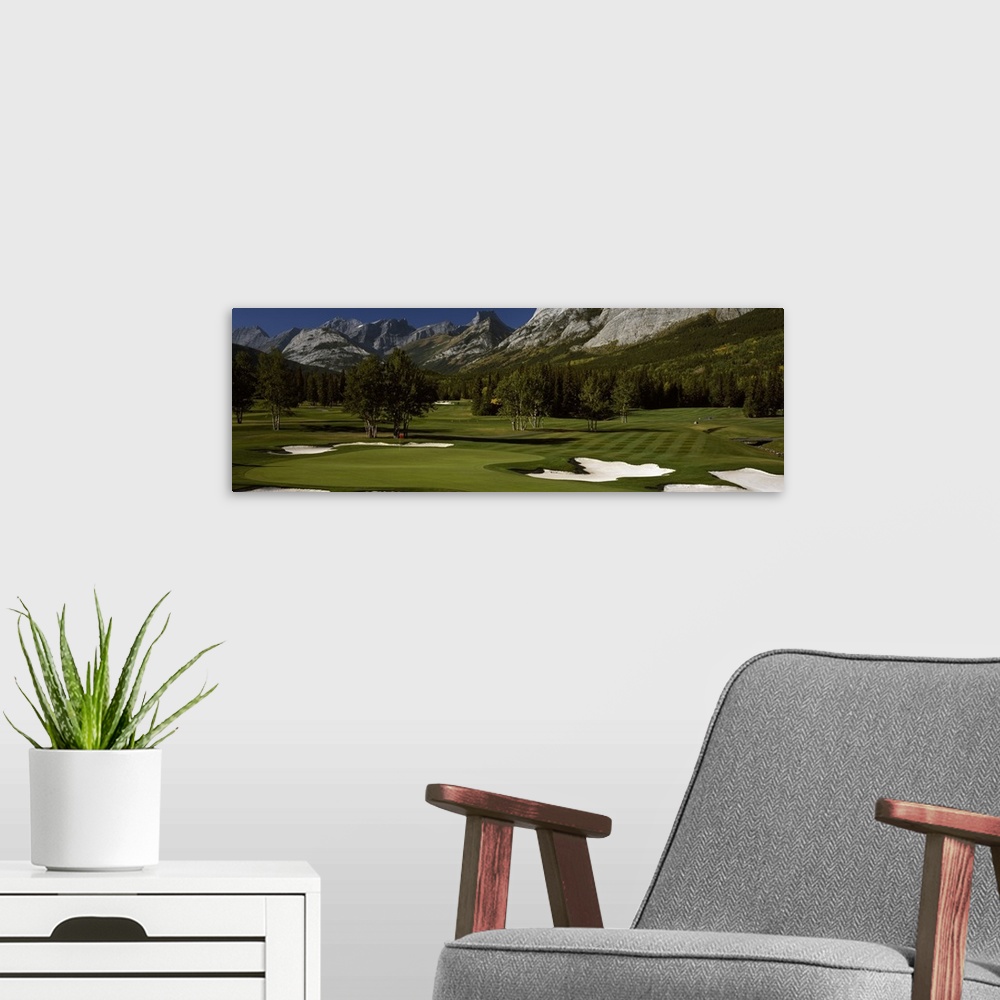 A modern room featuring Panoramic photograph taken on a golf course of one of the holes that is surrounded by a mountain ...