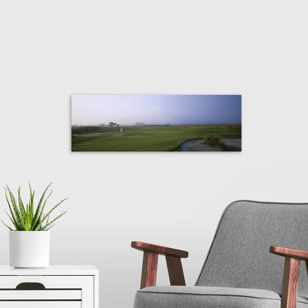 A modern room featuring Giant landscape photograph of a flag surrounded by the rolling greens on Ocean Golf Course, benea...