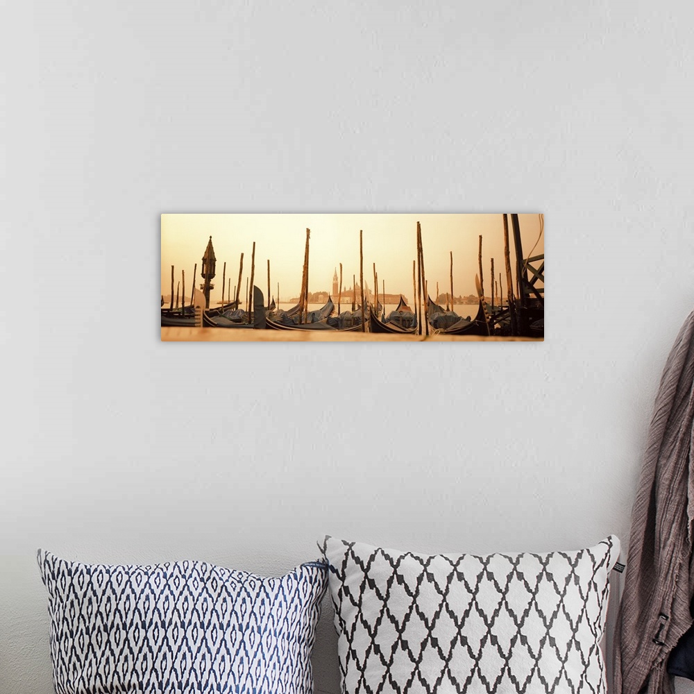 A bohemian room featuring A line of gondola boats are photographed in panoramic view as they sit docked in the water.