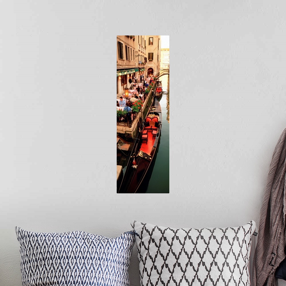 A bohemian room featuring Vertical panoramic photograph boats on canal waterway lined with street cafes and buildings.