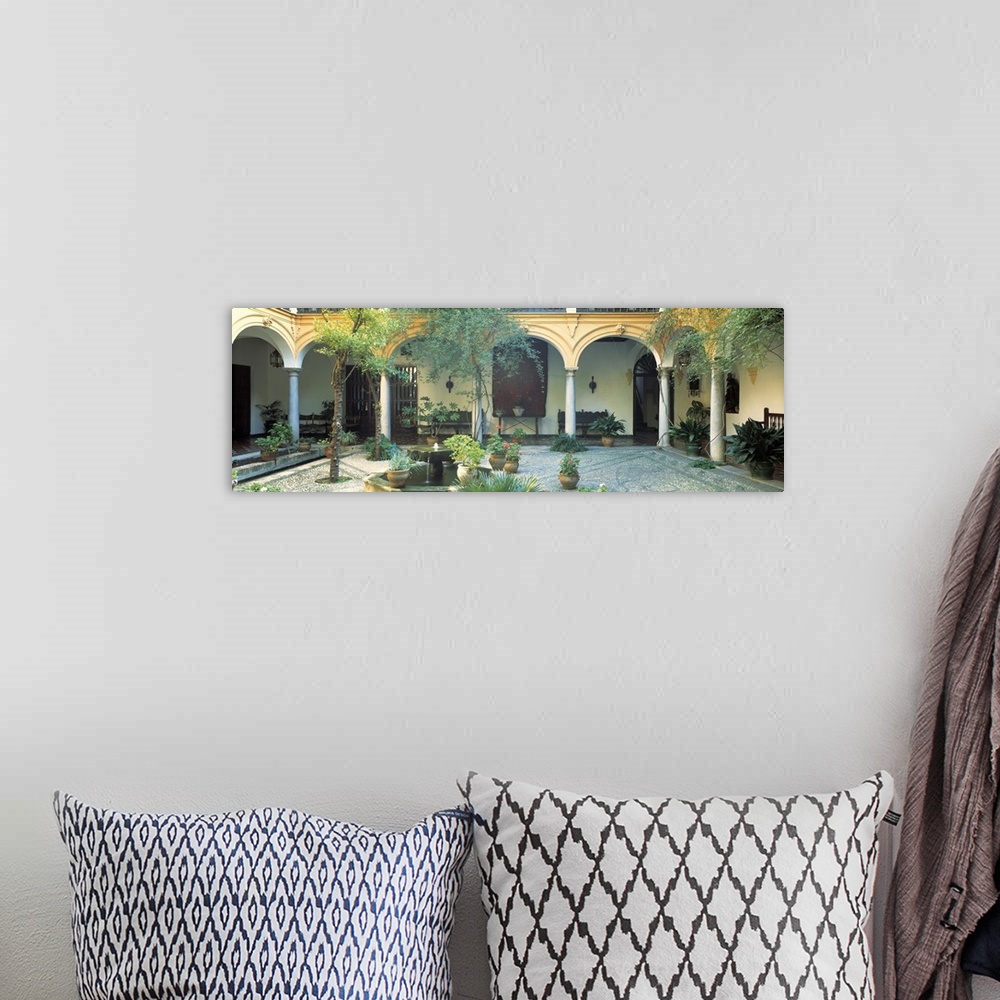 A bohemian room featuring Long photo on canvas of a Spanish courtyard garden with a bunch of potted plants.