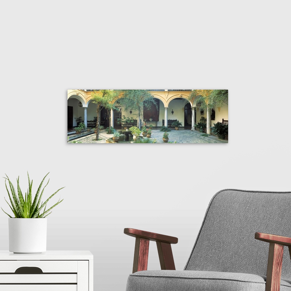 A modern room featuring Long photo on canvas of a Spanish courtyard garden with a bunch of potted plants.
