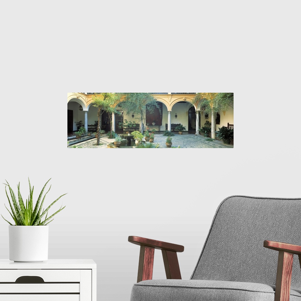 A modern room featuring Long photo on canvas of a Spanish courtyard garden with a bunch of potted plants.