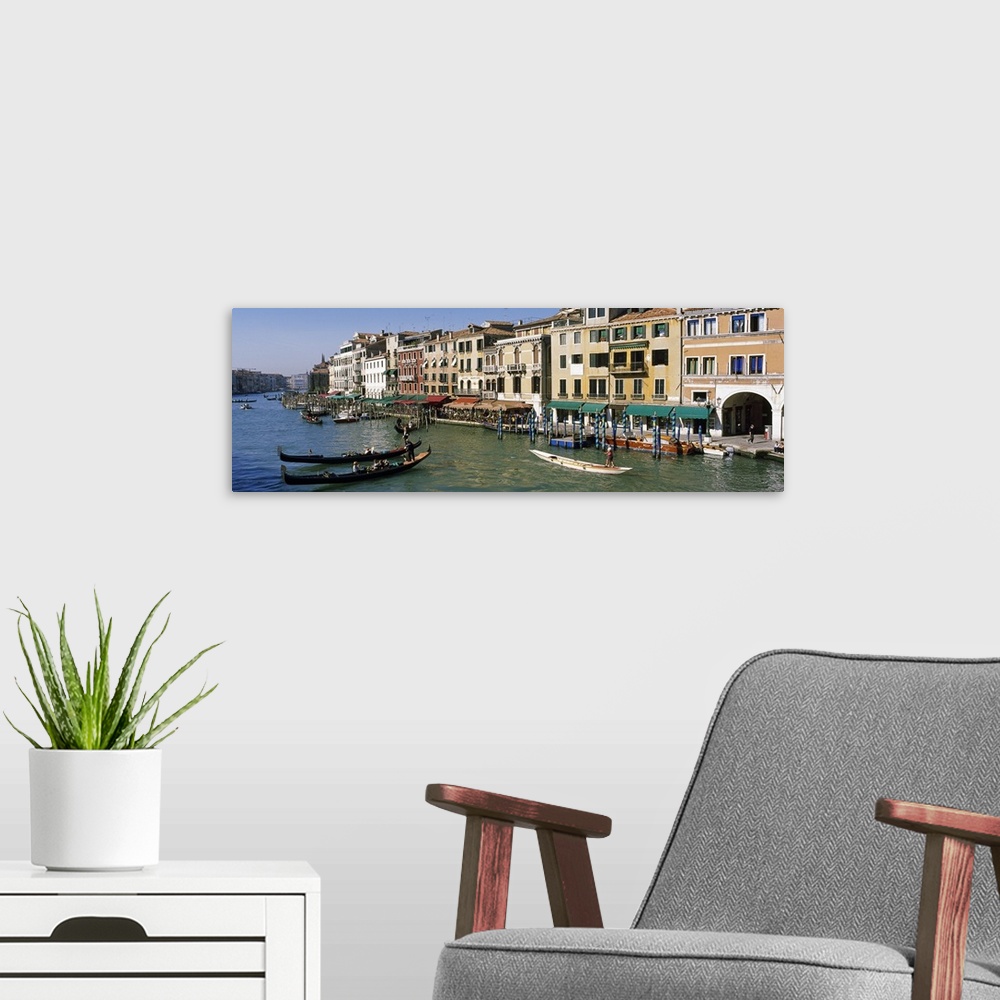 A modern room featuring Large panoramic of a busy canal in Venice, Italy with gondola's and boats floating on the water a...