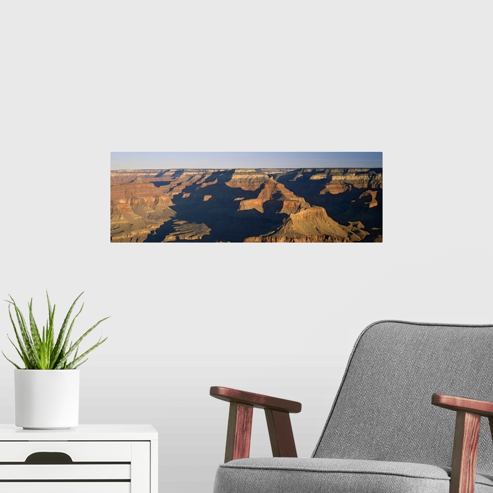 A modern room featuring Panoramic photograph of the large rock formations of the Grand Canyon in the golden sunlight, in ...