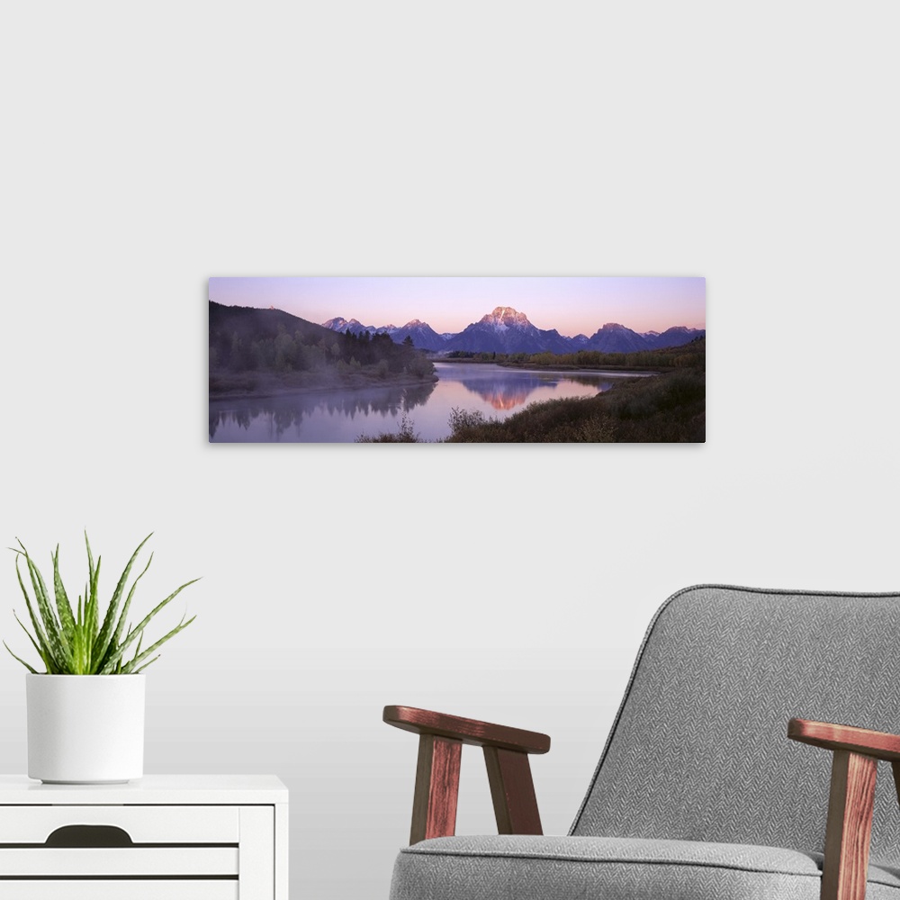 A modern room featuring Wide angle photograph taken from across a body of water looking out at a mountain range during su...