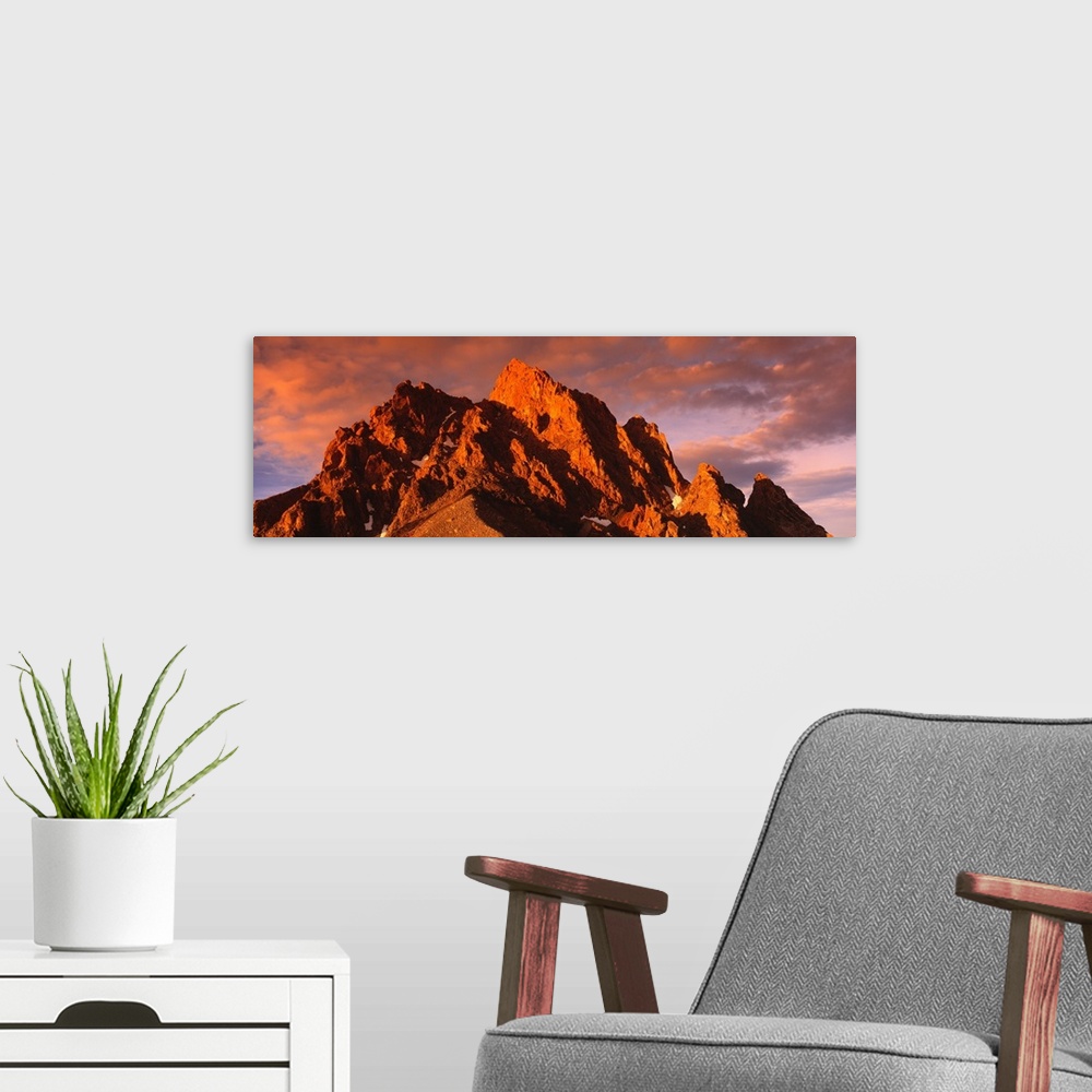 A modern room featuring Panoramic photograph of huge rock formation under a cloudy sky at dusk.