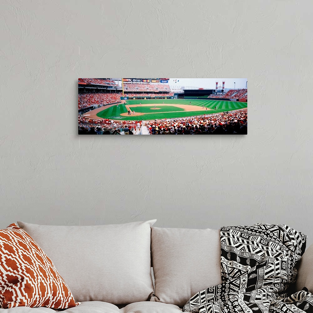 A bohemian room featuring A crowded baseball stadium photograph from near home plate on a panoramic canvas.