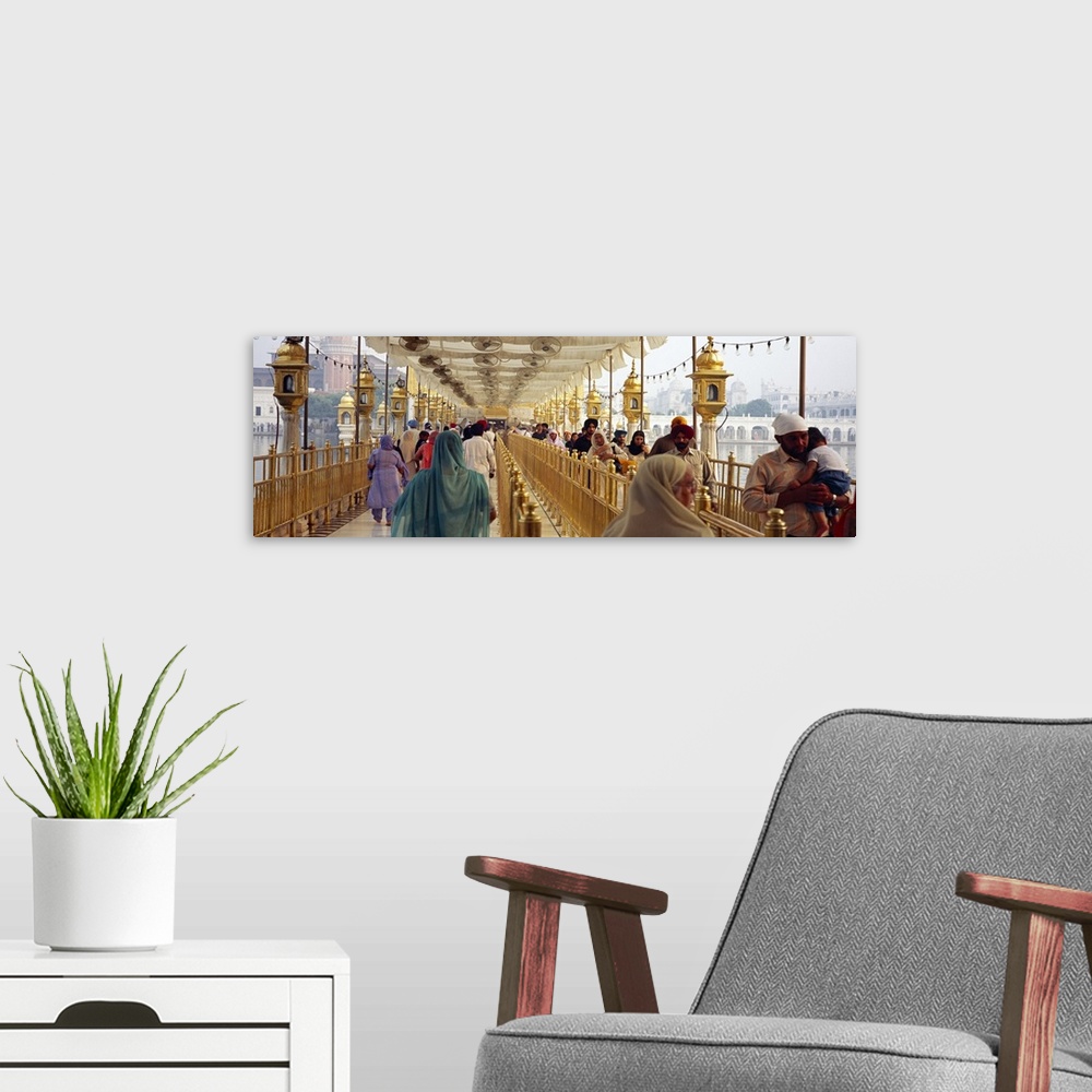 A modern room featuring Group of people walking on a bridge over a pond Golden Temple Amritsar Punjab India