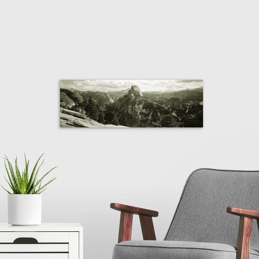 A modern room featuring Panoramic photograph of mountain range under a cloudy sky with cliff's edge in foreground.