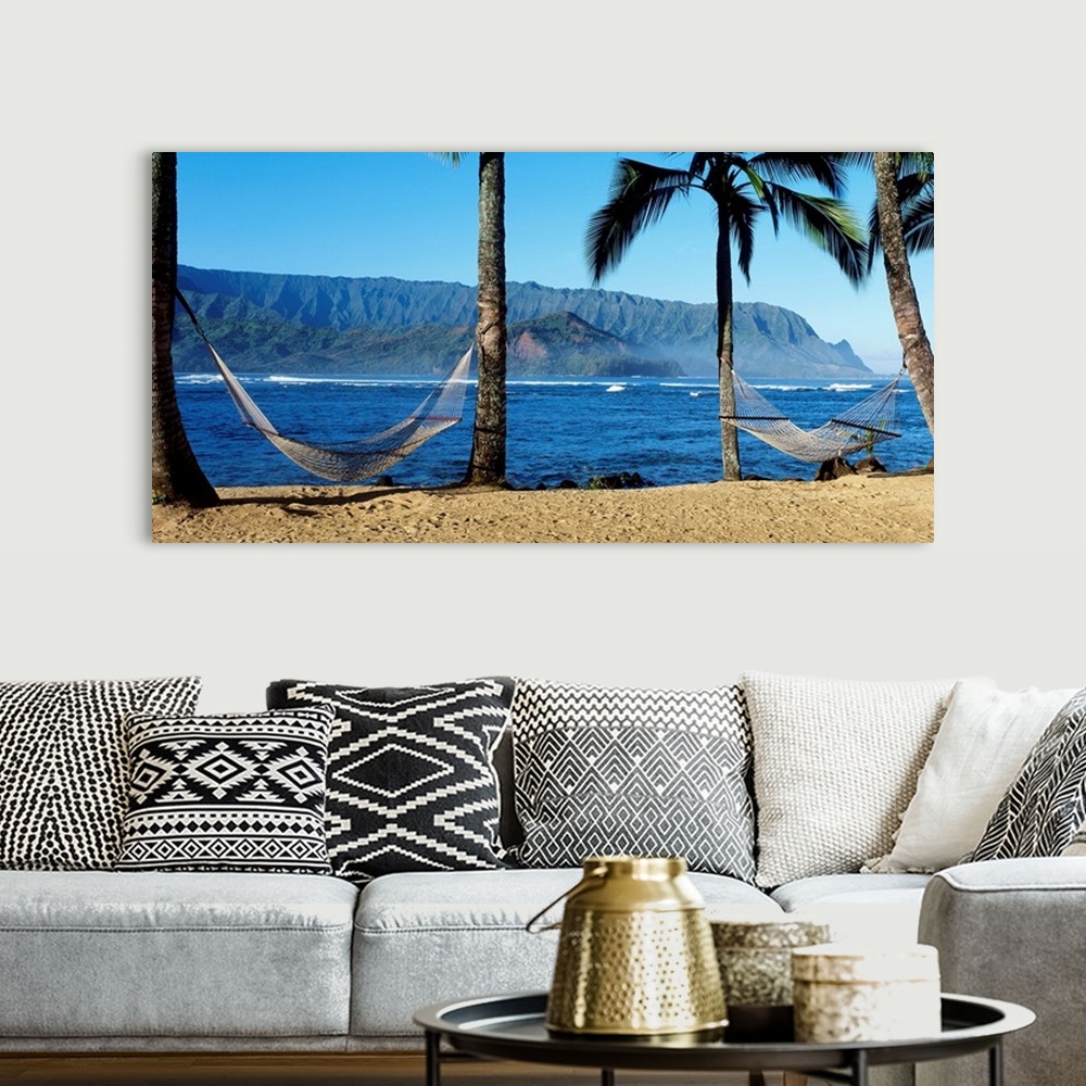A bohemian room featuring Panoramic photograph showcases a couple hammocks between palm trees on a beach within Hanalei Bay...
