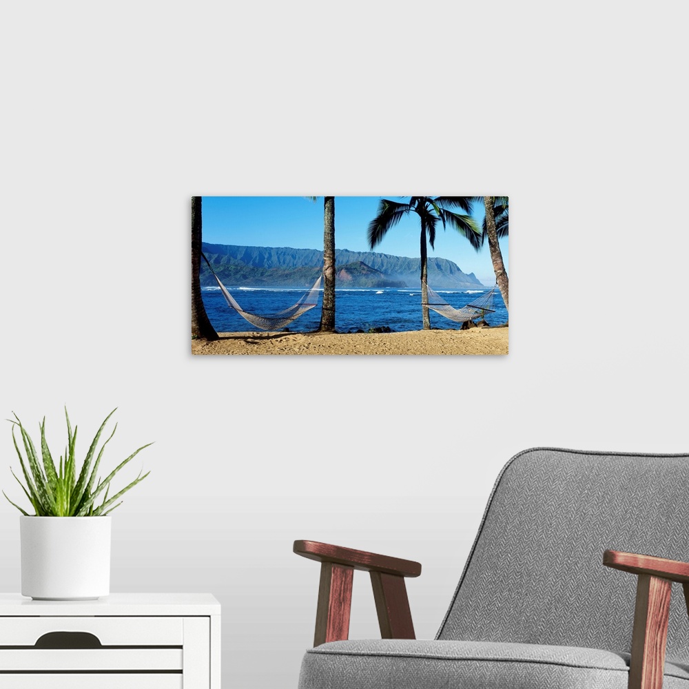 A modern room featuring Panoramic photograph showcases a couple hammocks between palm trees on a beach within Hanalei Bay...