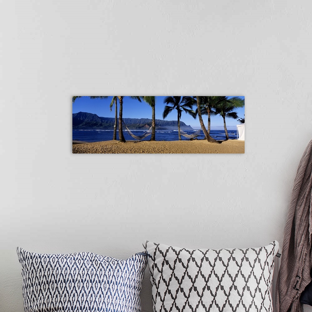 A bohemian room featuring Panoramic print of two hammocks swaying between palm trees along the ocean with mountains in the ...