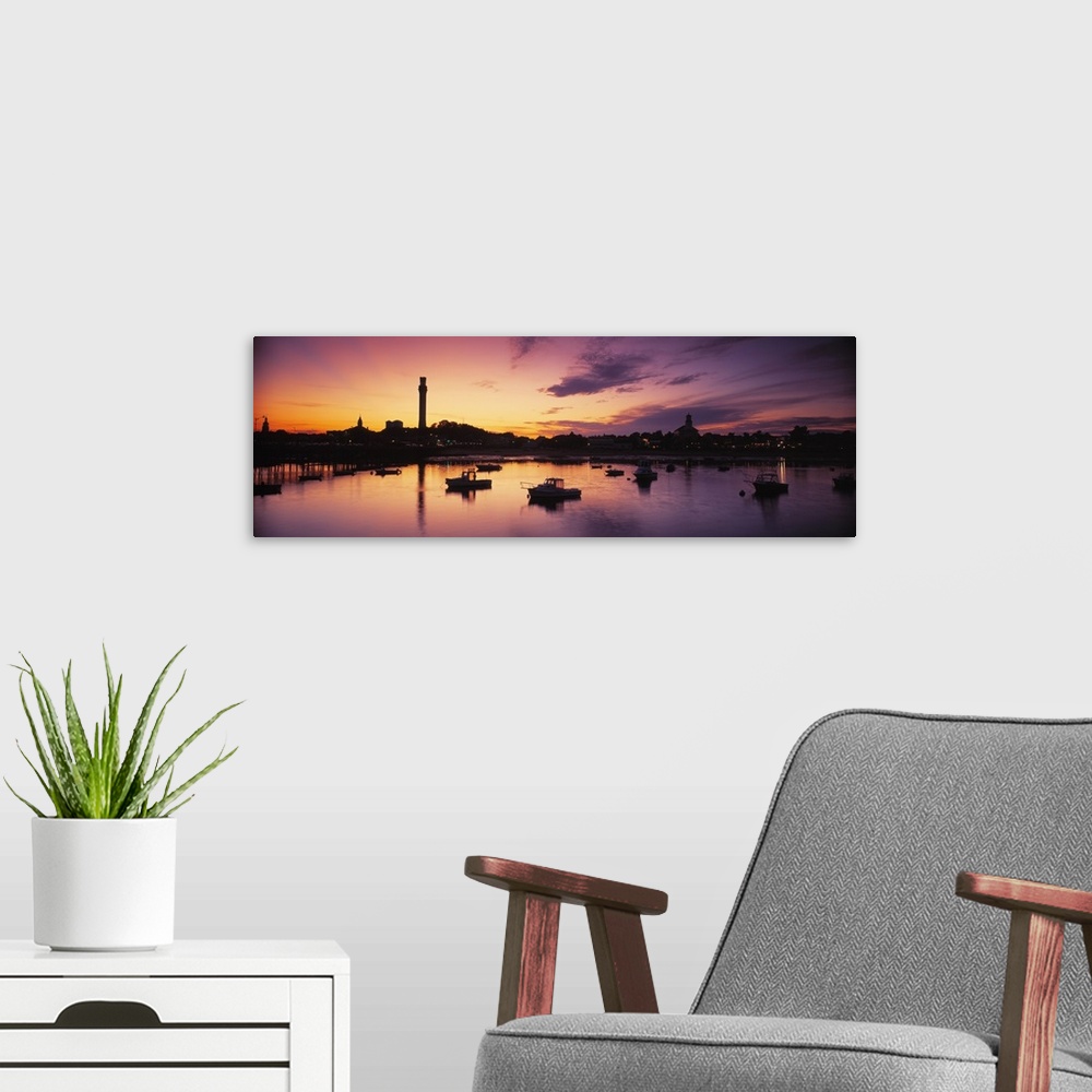 A modern room featuring Oversized photograph of the sun setting on the horizon as many boats in a harbor are silhouetted ...