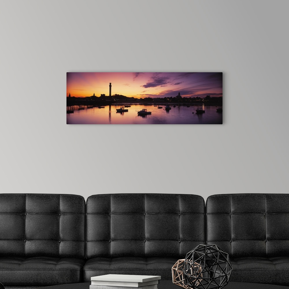 A modern room featuring Oversized photograph of the sun setting on the horizon as many boats in a harbor are silhouetted ...