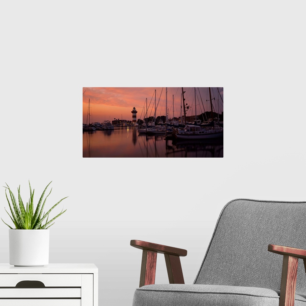 A modern room featuring Big photograph displays a marina full of sailboats and other watercraft docked under the dimming ...