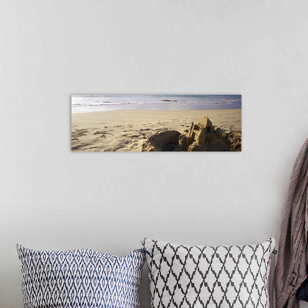 A bohemian room featuring This landscape photograph of a sandy beach has a elaborate well build castle in the foreground su...