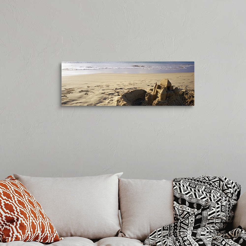 A bohemian room featuring This landscape photograph of a sandy beach has a elaborate well build castle in the foreground su...