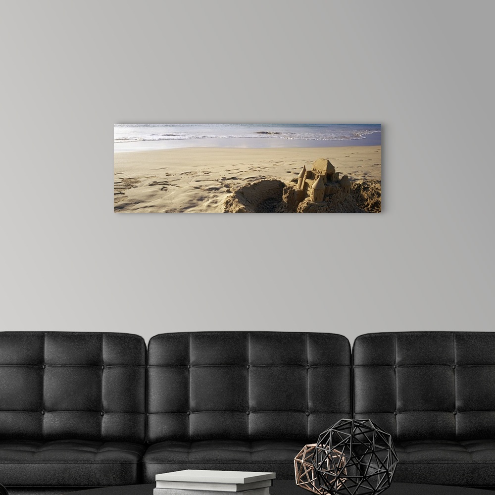 A modern room featuring This landscape photograph of a sandy beach has a elaborate well build castle in the foreground su...