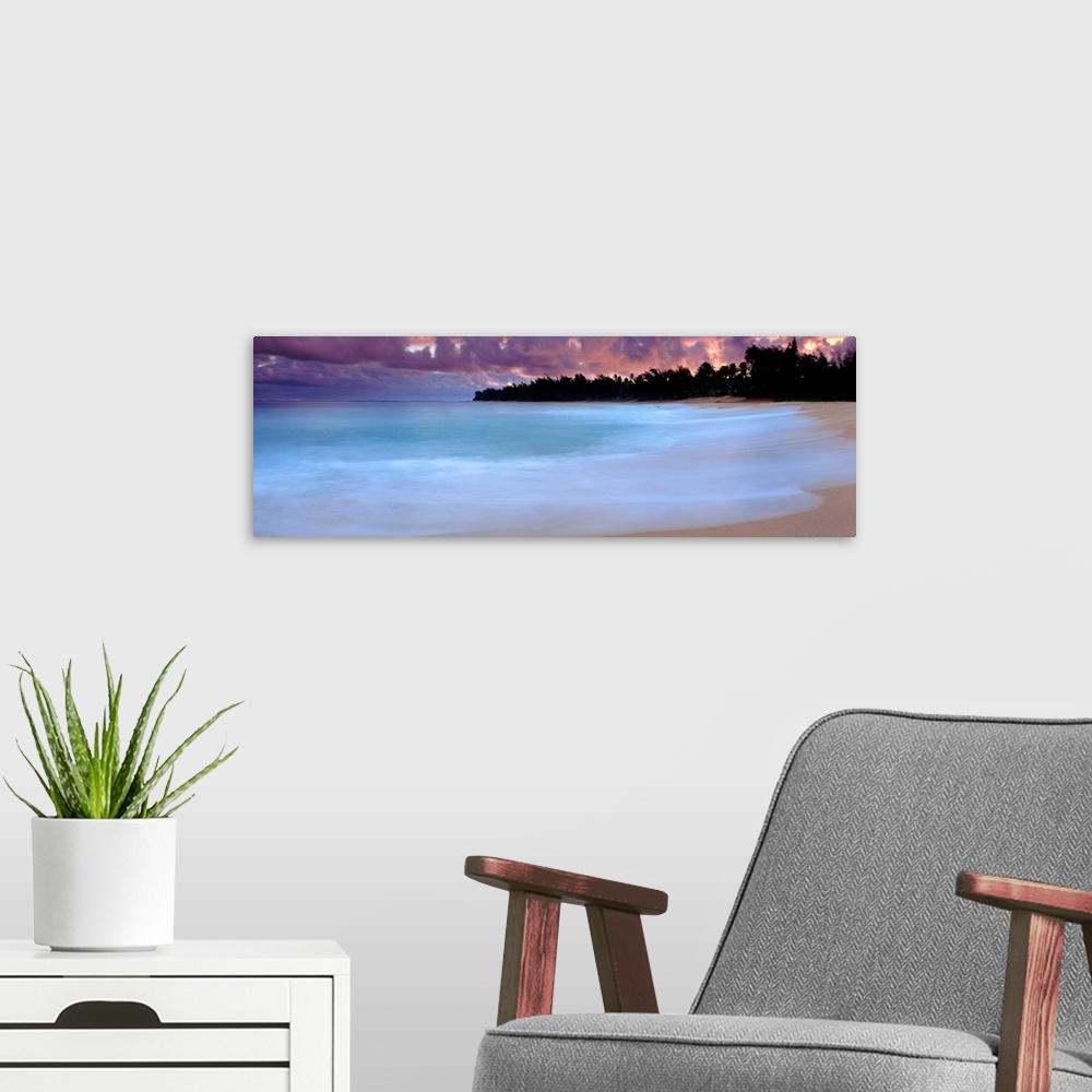 A modern room featuring A time lapsed photograph of waves lapping against a sandy tropical beach with the silhouetted of ...