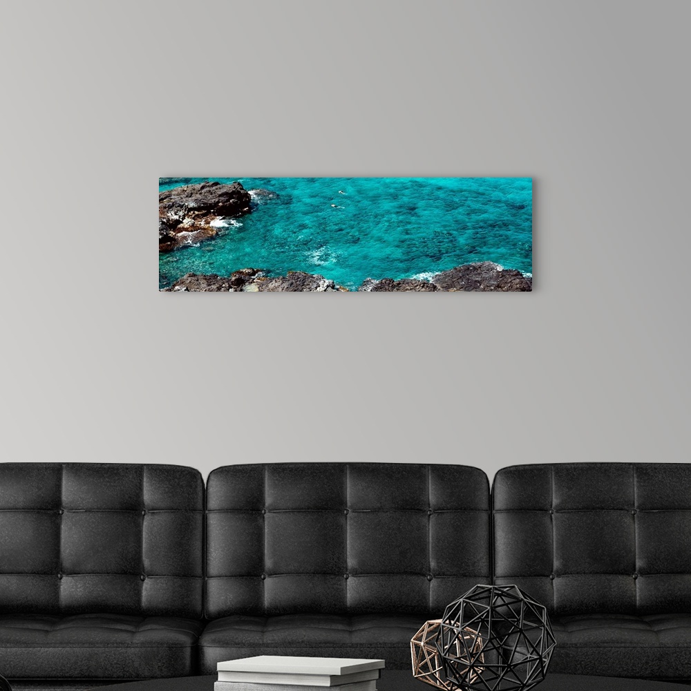 A modern room featuring This panoramic photograph shows two figures from distance in clear waters of a reef.