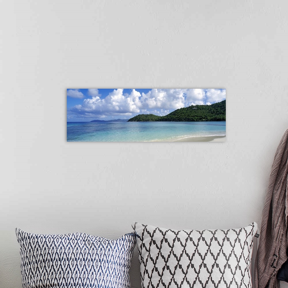 A bohemian room featuring Panoramic photo on canvas of a clear ocean meeting a shore with rolling hills on the right side.