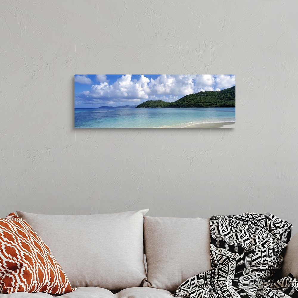 A bohemian room featuring Panoramic photo on canvas of a clear ocean meeting a shore with rolling hills on the right side.