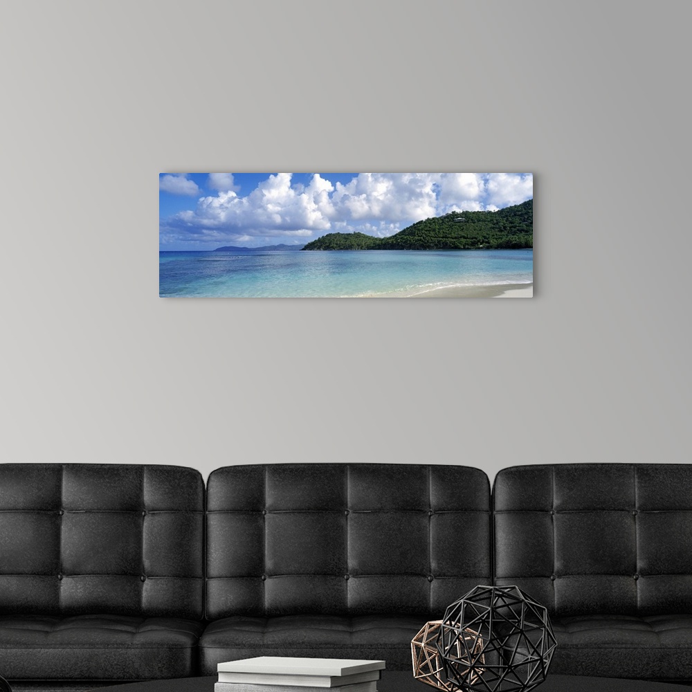 A modern room featuring Panoramic photo on canvas of a clear ocean meeting a shore with rolling hills on the right side.
