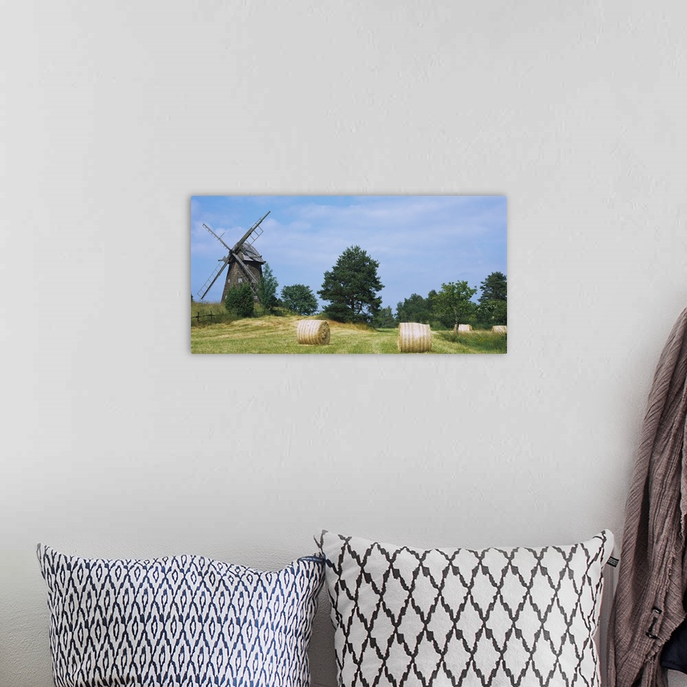 A bohemian room featuring Hay bale in a field with a traditional windmill in the background, Riddarfjarden, Narke, Sweden