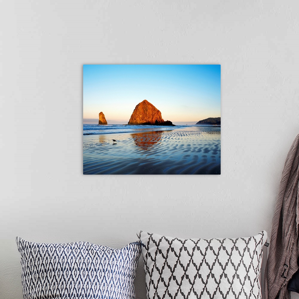 A bohemian room featuring Giant photograph taken of a huge rock sitting on the edge of a beach on a sunny day.  In the back...