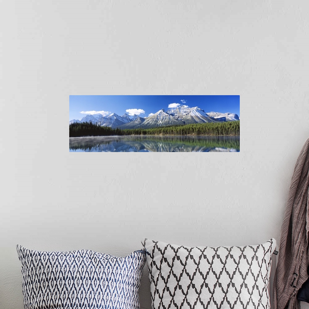 A bohemian room featuring Large panoramic canvas of big snowy mountains with a dense forest beneath it reflected in the water.
