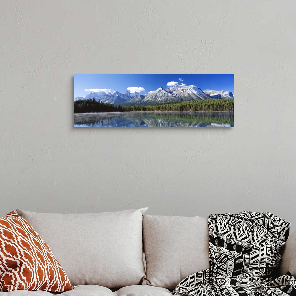 A bohemian room featuring Large panoramic canvas of big snowy mountains with a dense forest beneath it reflected in the water.