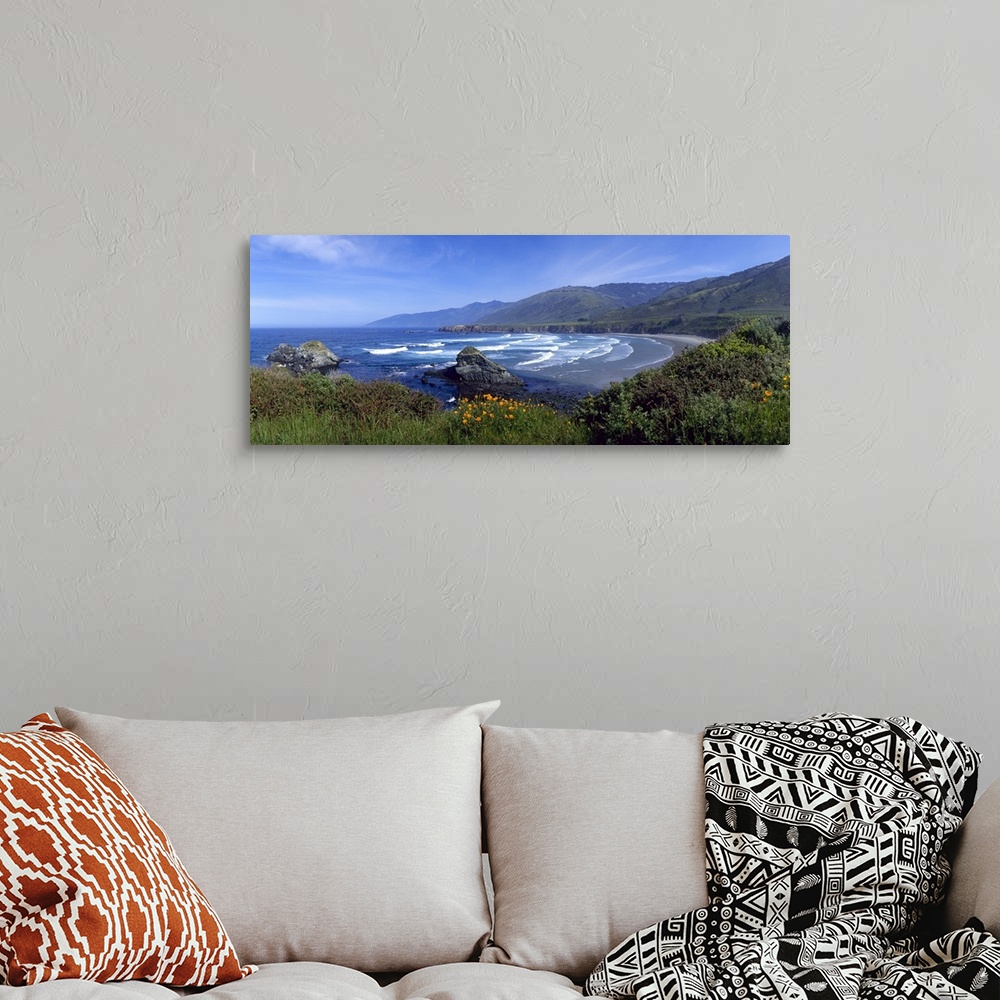 A bohemian room featuring Panoramic photograph of cove surrounded by tall grass and mountains fading into the distance.  Th...