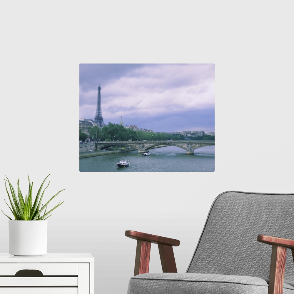 A modern room featuring Horizontal photograph on a large canvas of  two small boats that have passed below a bridge on th...