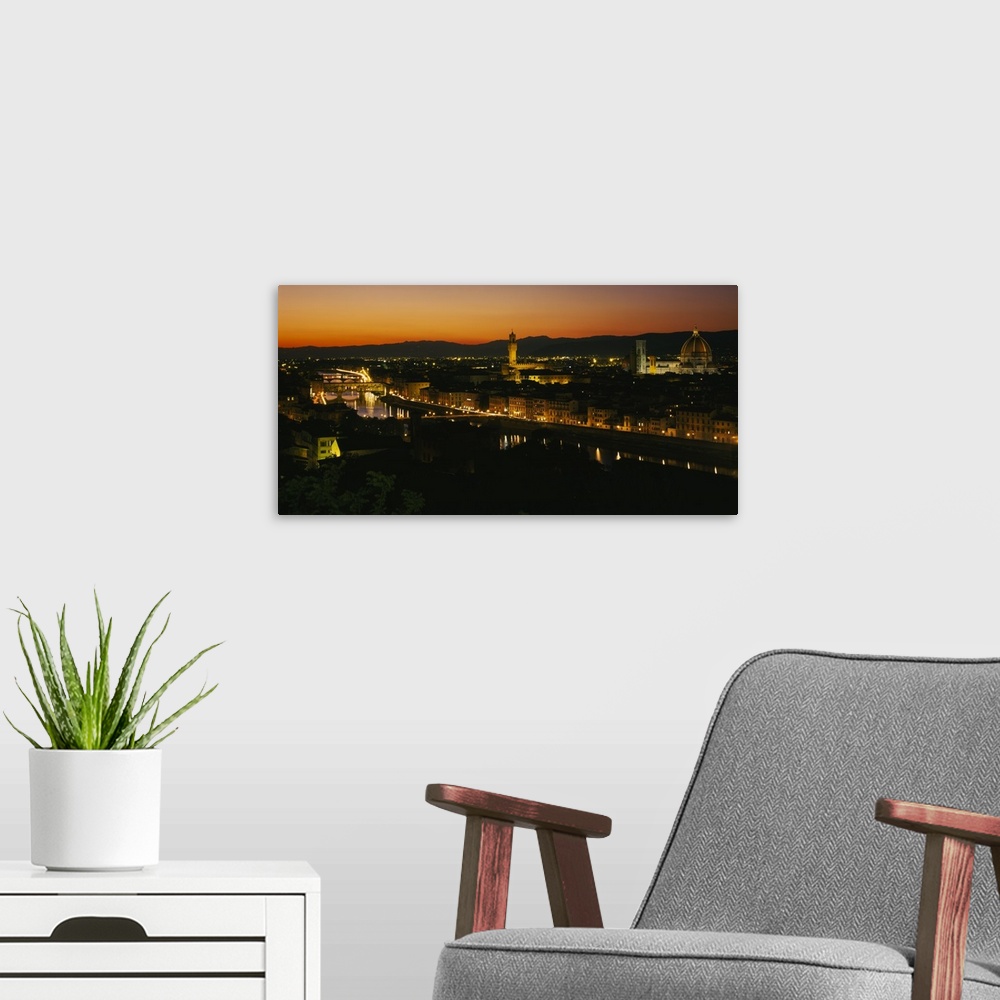 A modern room featuring Panoramic photograph of lit up skyline with mountain silhouettes in the distance at sunset.