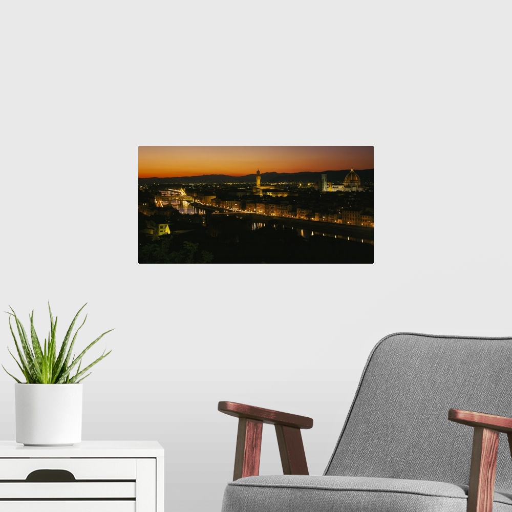 A modern room featuring Panoramic photograph of lit up skyline with mountain silhouettes in the distance at sunset.