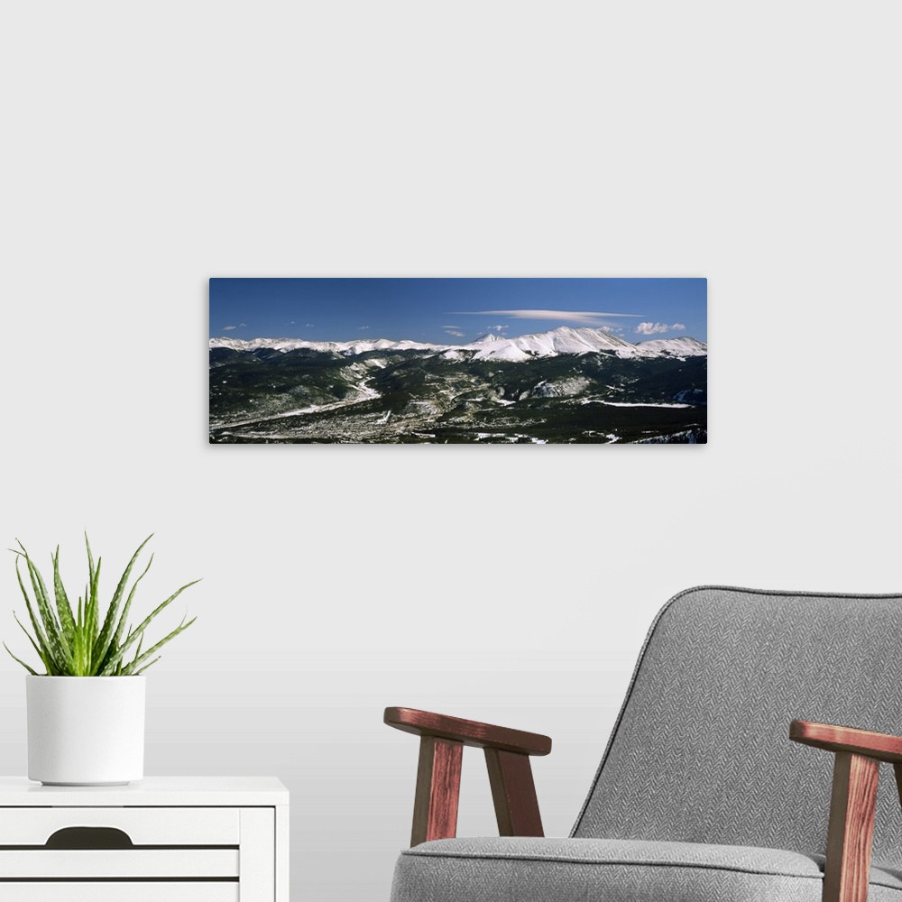 A modern room featuring This wide angle photograph is an aerial shot of a snow covered mountain range with vast land and ...