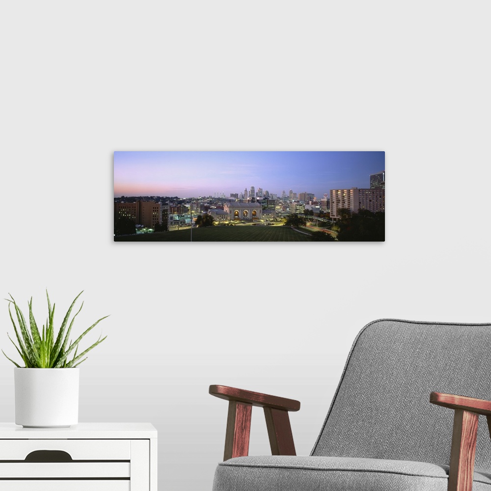 A modern room featuring Wide angle photograph taken of the Kansas City skyline with the buildings illuminated under a dus...