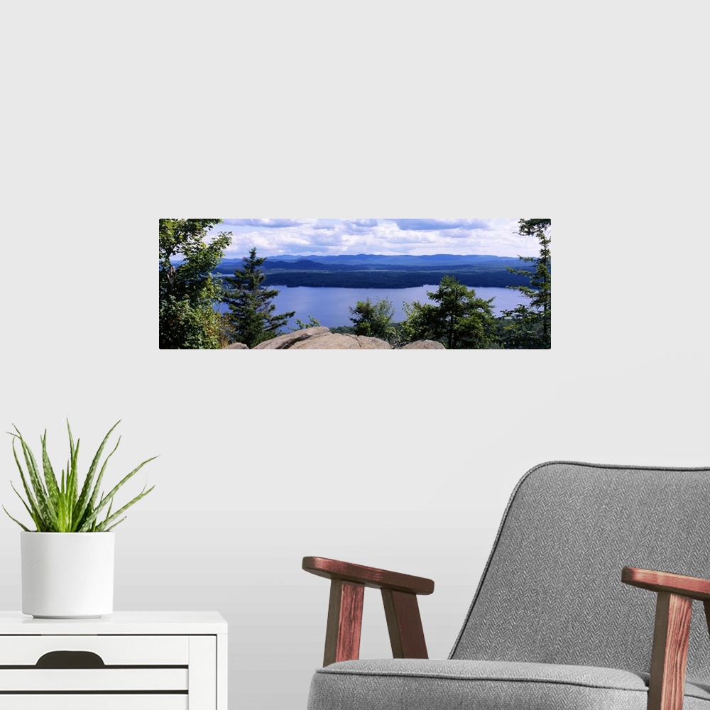 A modern room featuring Panoramic photograph of huge rock with surrounded by forest with river in the background and moun...