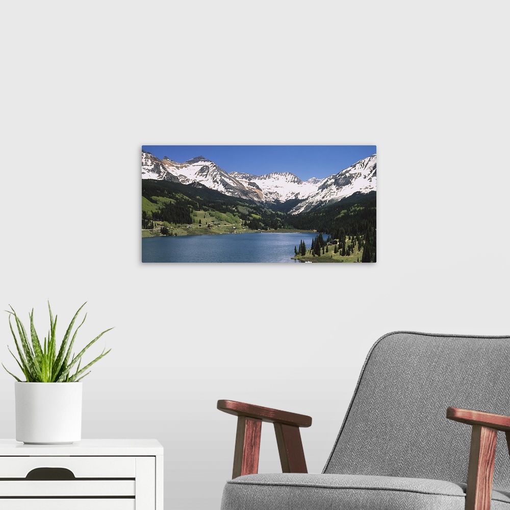 A modern room featuring Big photograph shows a range of snow-capped mountains surrounding a large body of water.  About h...