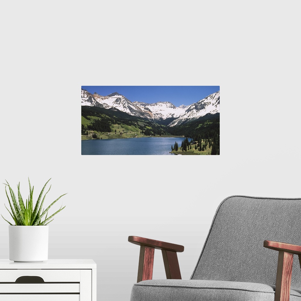 A modern room featuring Big photograph shows a range of snow-capped mountains surrounding a large body of water.  About h...